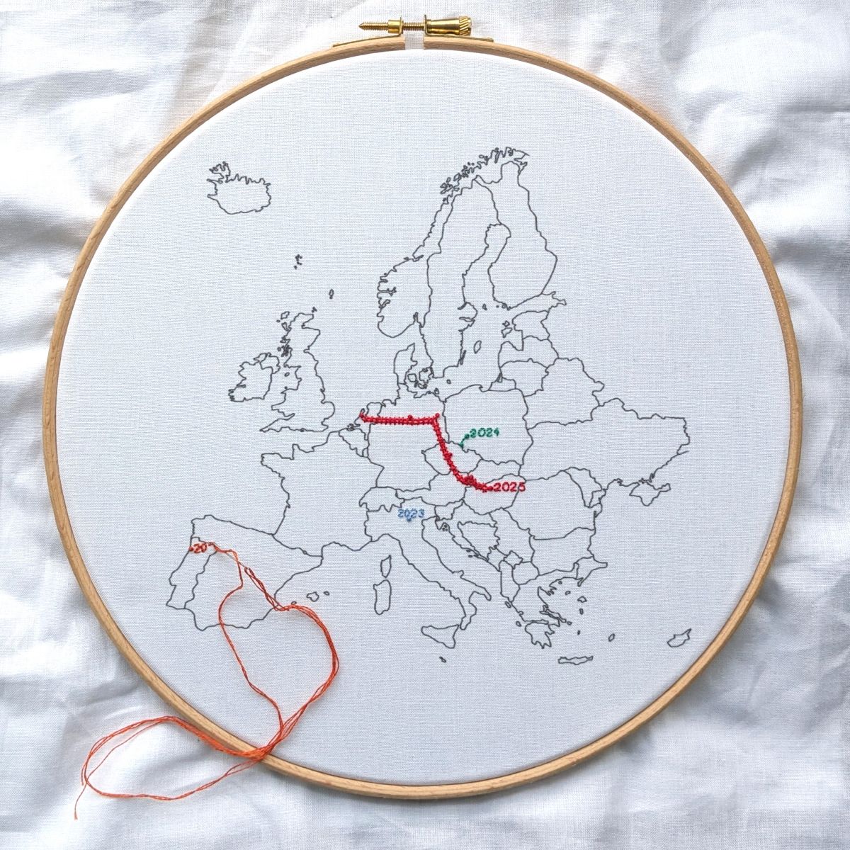 An Embroidery hoop holding white fabric with a map of Europe on it